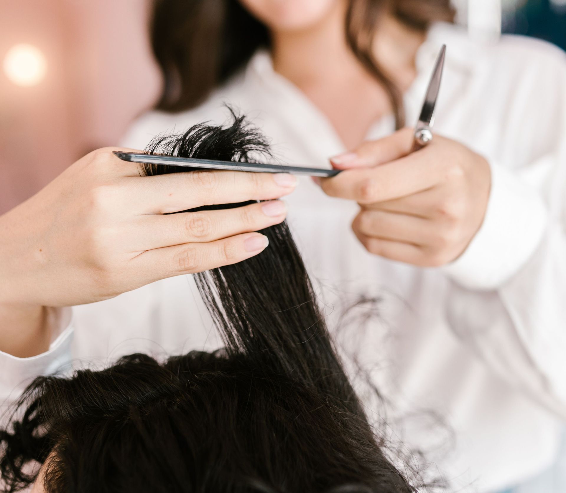 Close-up of hairstylist expertly cutting client’s hair in a salon setting.